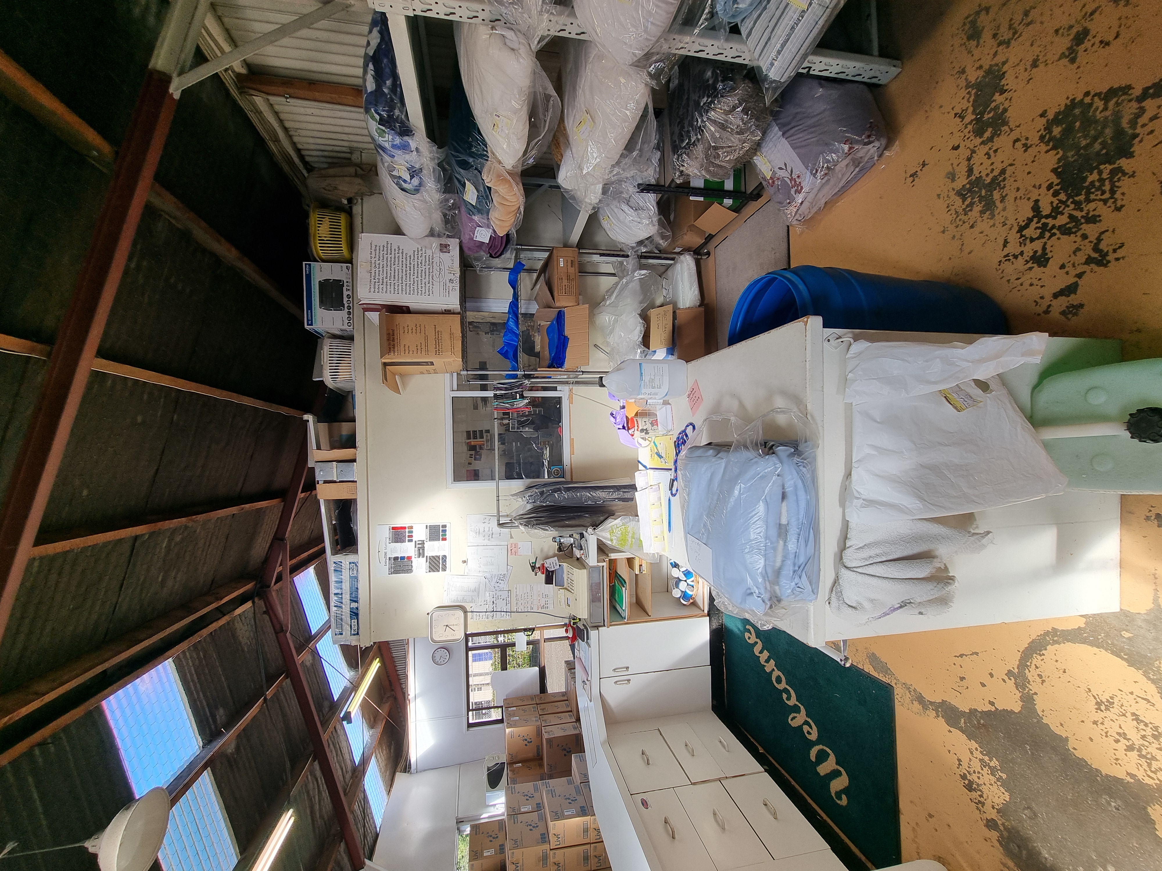 An area with a reception desk, back wall of the office and some shelves with folded laundry