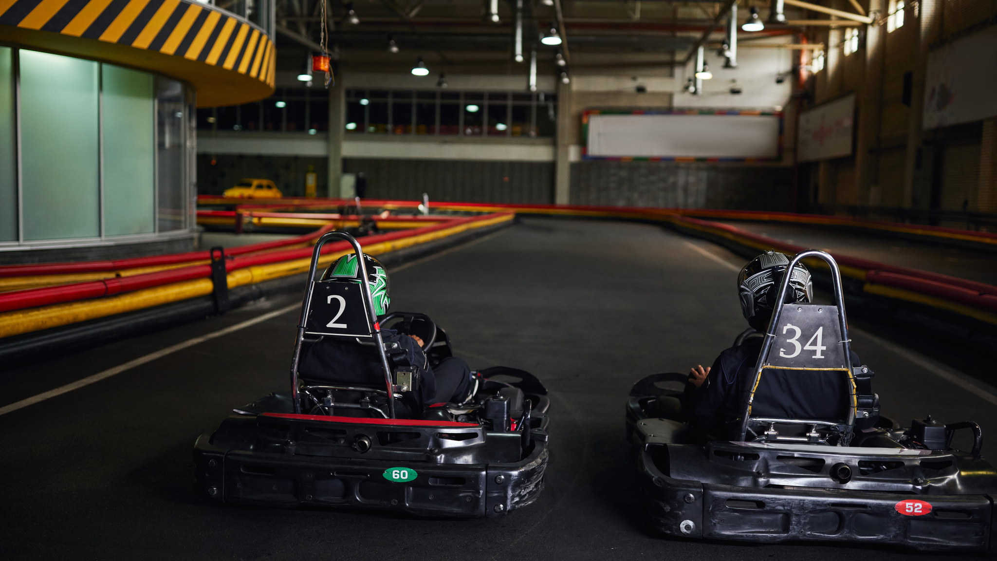 Dos karts uno al lado del otro en una pista cubierta de un centro de entretenimiento familiar.