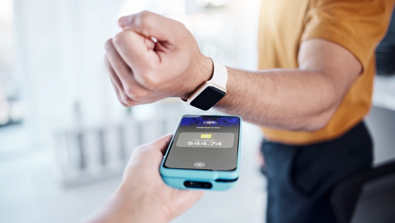 A guest paying by holding a smartwatch to an iPhone running GoTab