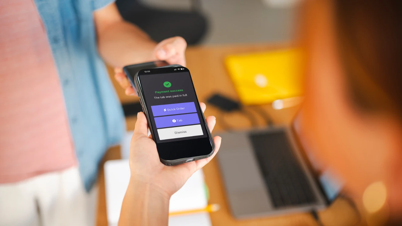 A staff member showing a guest an iPhone with a GoTab payment confirmation