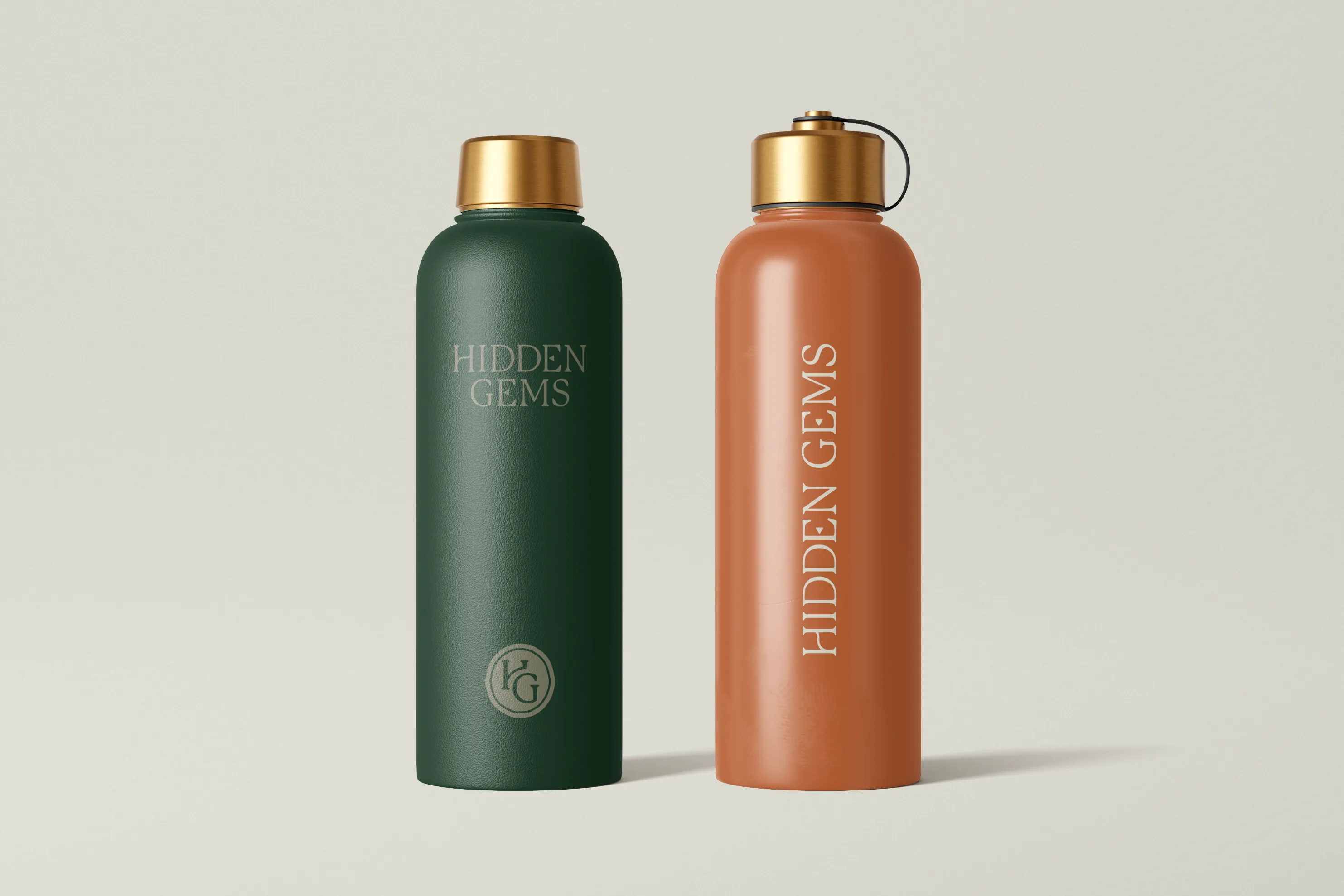 Two insulated metal water bottles with gold caps, one green and one brown, both labeled Hidden Gems.