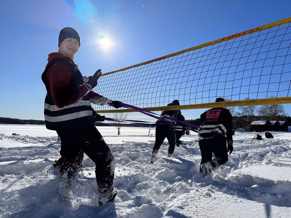 Uteträning i snön varav ena killen drar en annan kille med hjälp av ett band