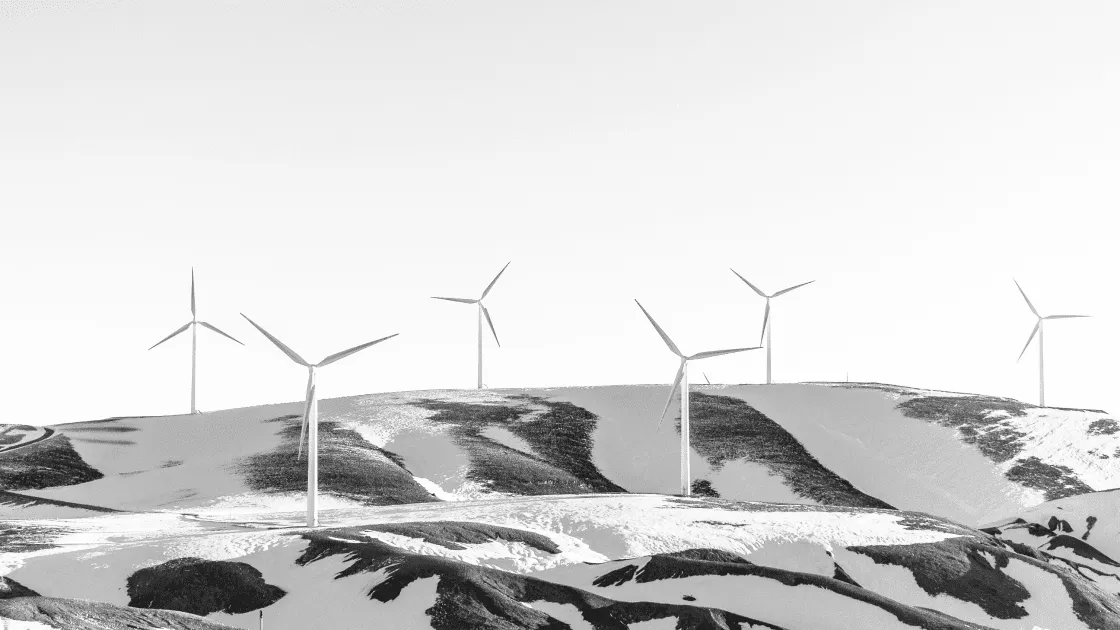 A hillside covered in snow and a field of wind turbines