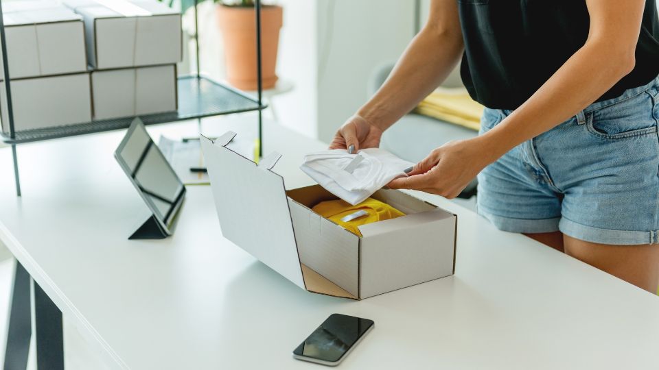 A woman packing her merchandise into boxes.