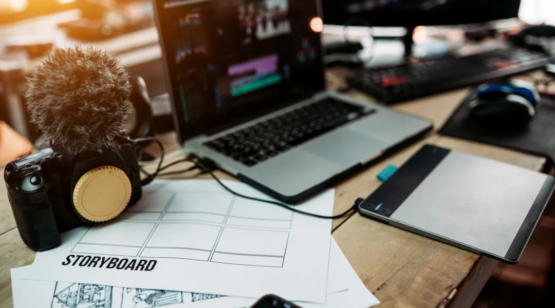 A desk with a storyboard paper, a camera, and a laptop with Premiere Pro open