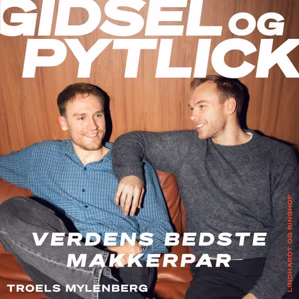 To mænd sidder afslappet sammen på en sofa og smiler til hinanden.