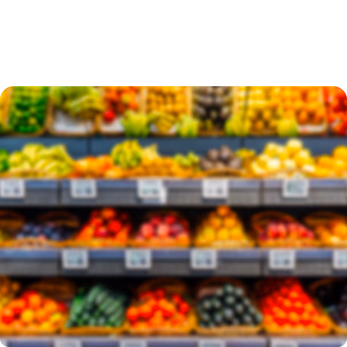 Blurry display of various fruits and vegetables arranged on shelves in a grocery store produce section.