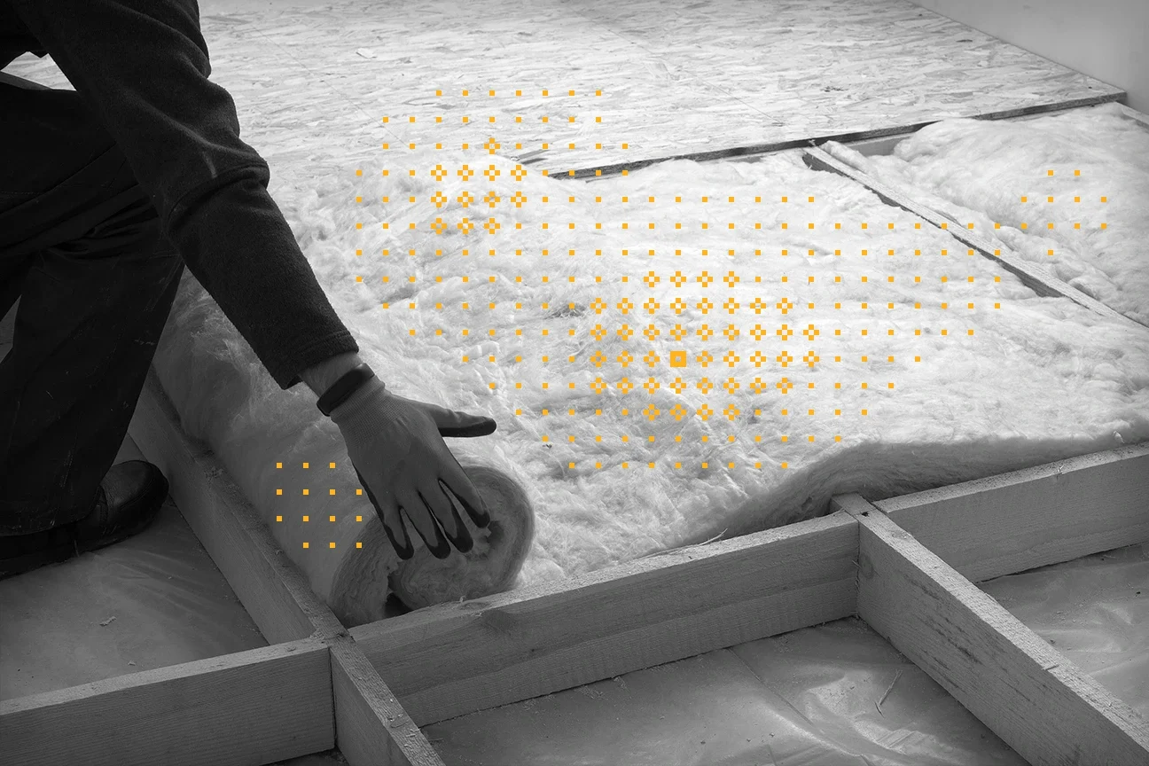 black and white photo of contractor installing insulation in a home with yellow decorative glyphs over the insulation