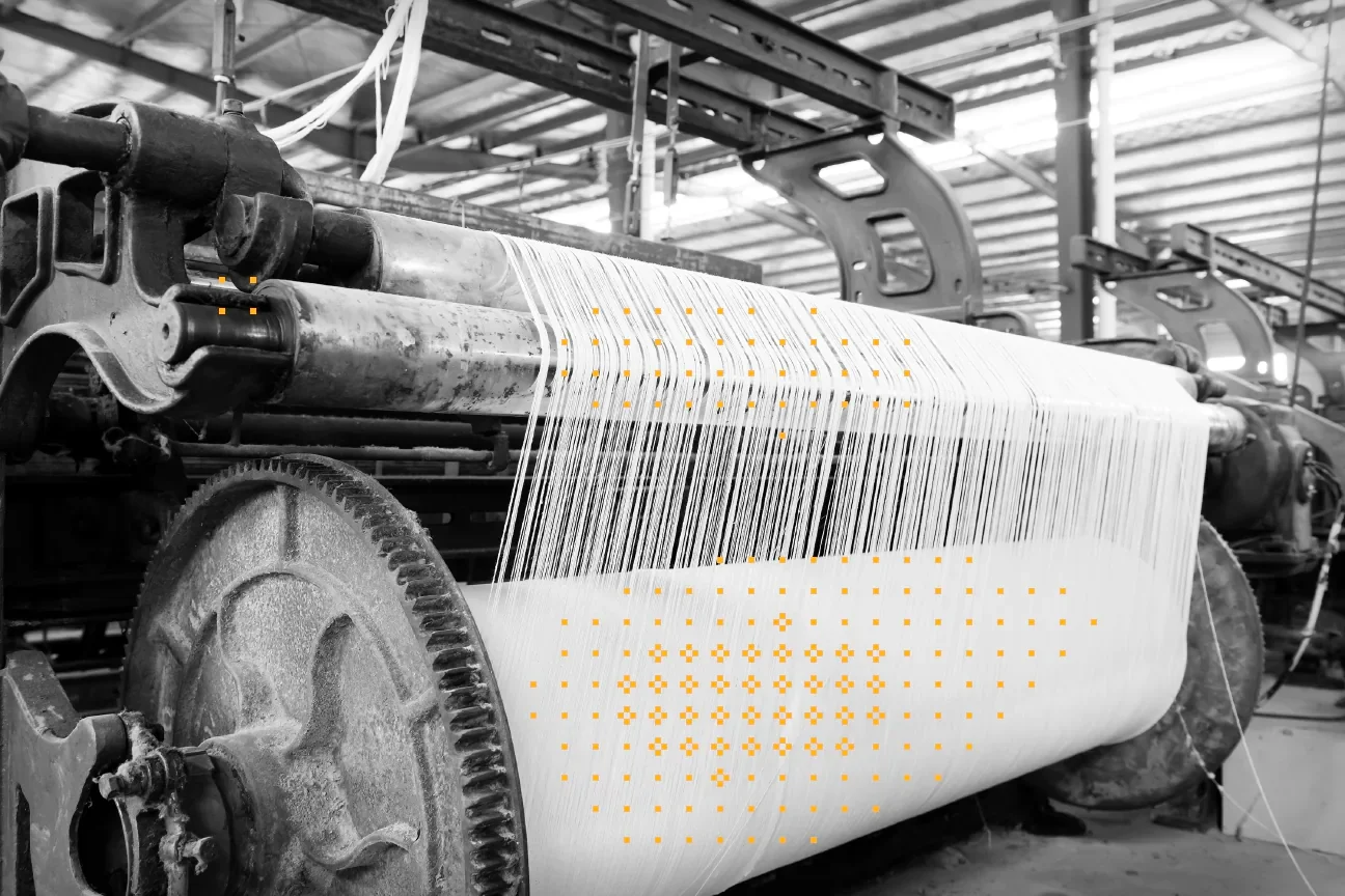 black and white photo of an industrial loom with yellow flourishes on the fabric