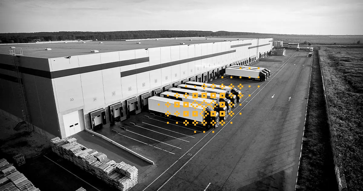 photo en noir et blanc de camions garés à l'extérieur d'un centre de distribution avec des glyphes décoratifs jaunes sur les camions