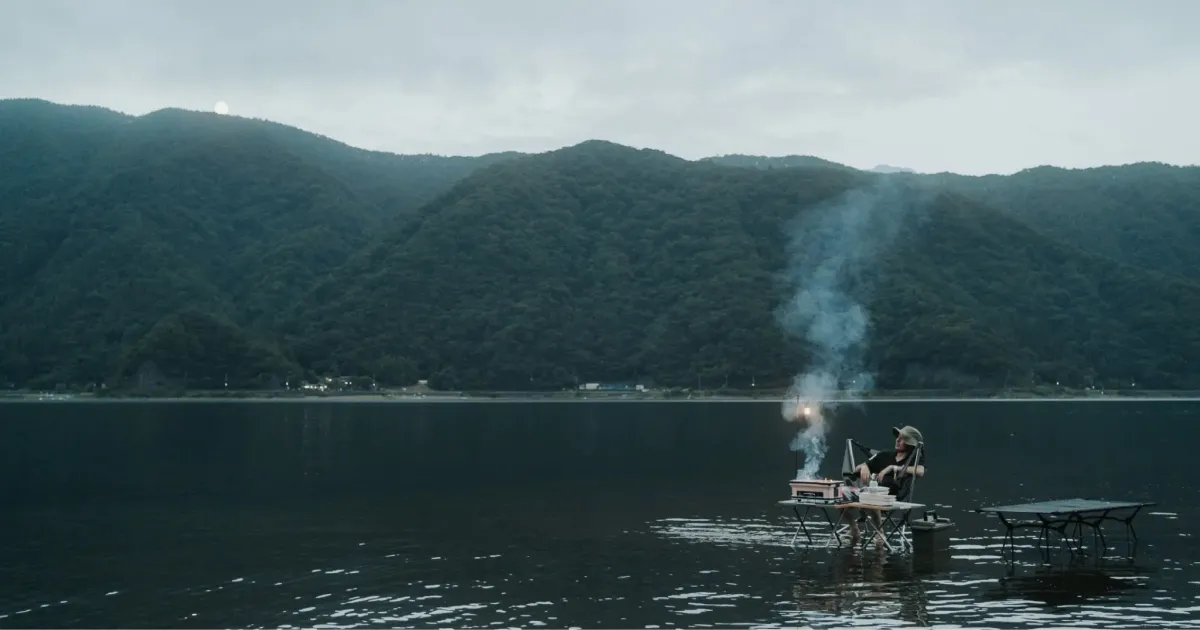 A Photo of Nobu grilling fish on a lake.