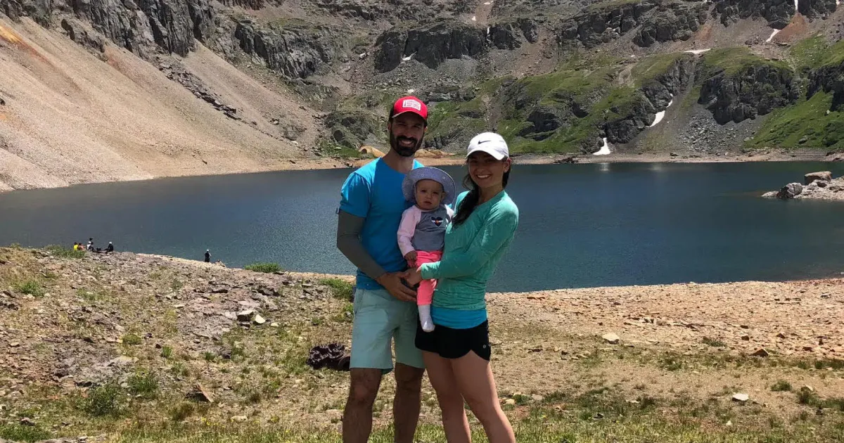 Natalia and family standing next to a mountain lake