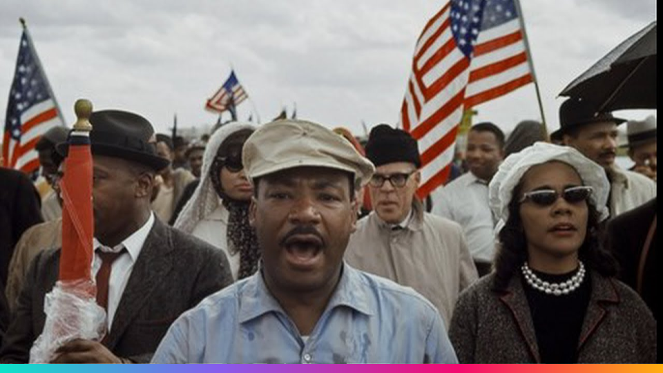 Crowd of diverse people, some holding American flags, during a civil rights march.