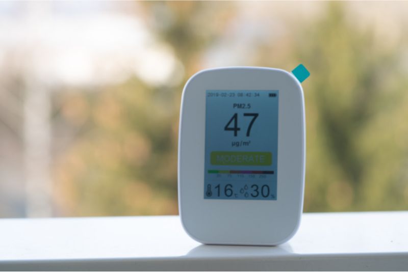 person using small handheld device to test air quality