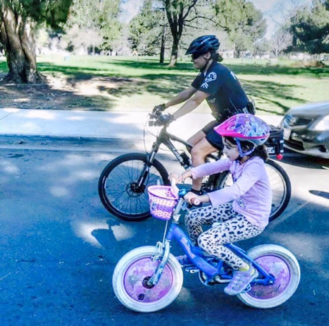 LAPD Female Bike Officer riding a bike with a child bicyclist.