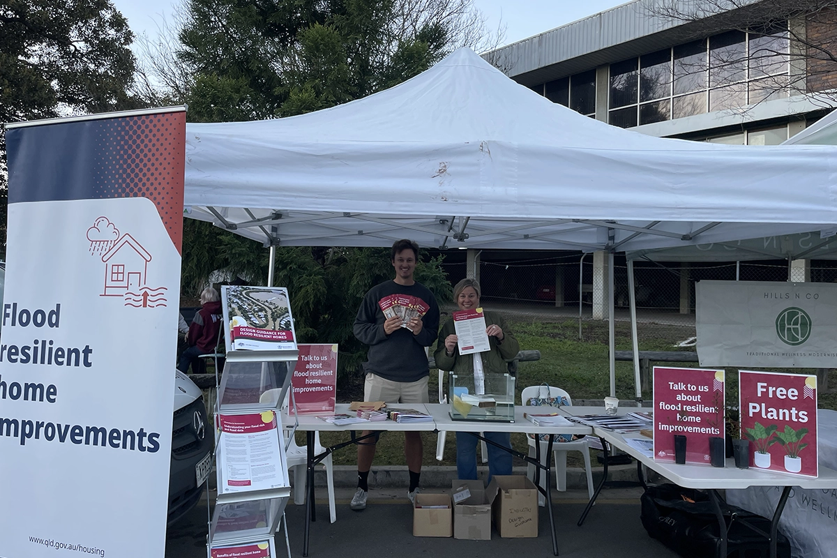 A young man facilitating a consultation, holding up an information sheet in front of some posters with sticky notes on them.