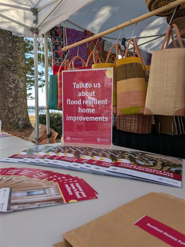 Flood resiliency booklets and flyers spread out across a table under a marquee