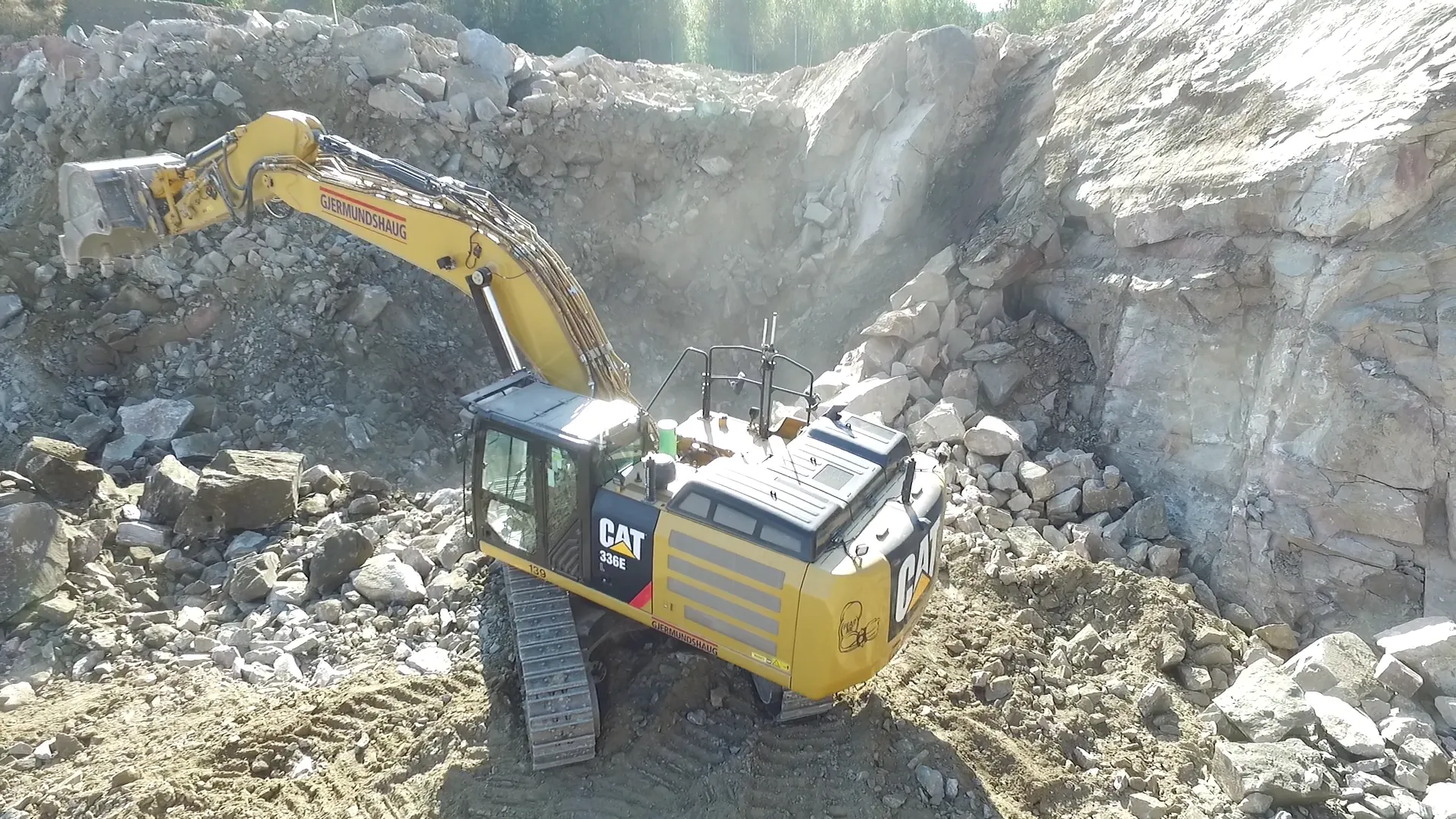 Caterpillar 336E excavator clearing misfired explosives in a rocky quarry during the Misfire Clearing project