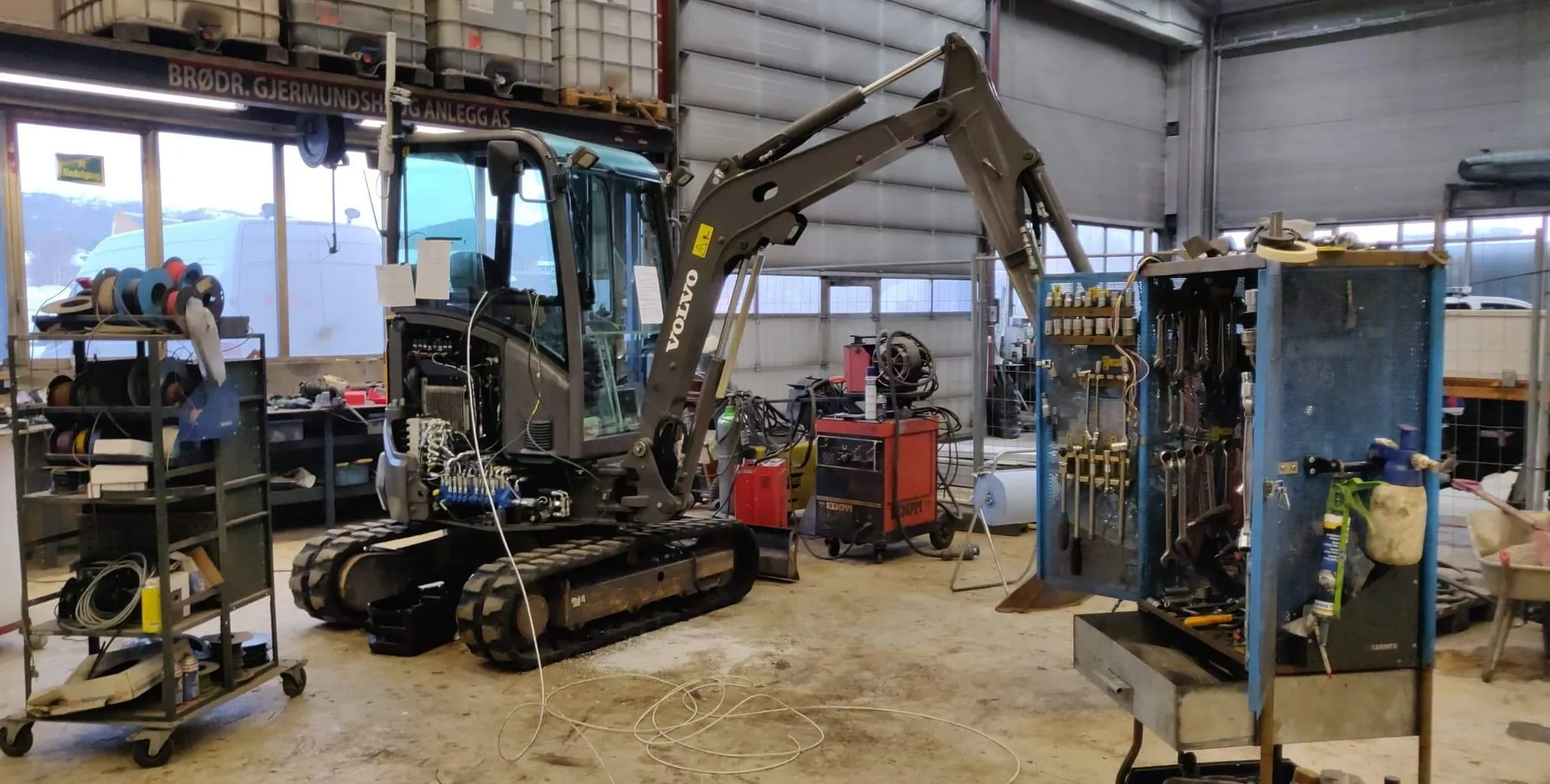 Volvo compact excavator undergoing hydraulic system maintenance in a workshop during the Sylling Substation project