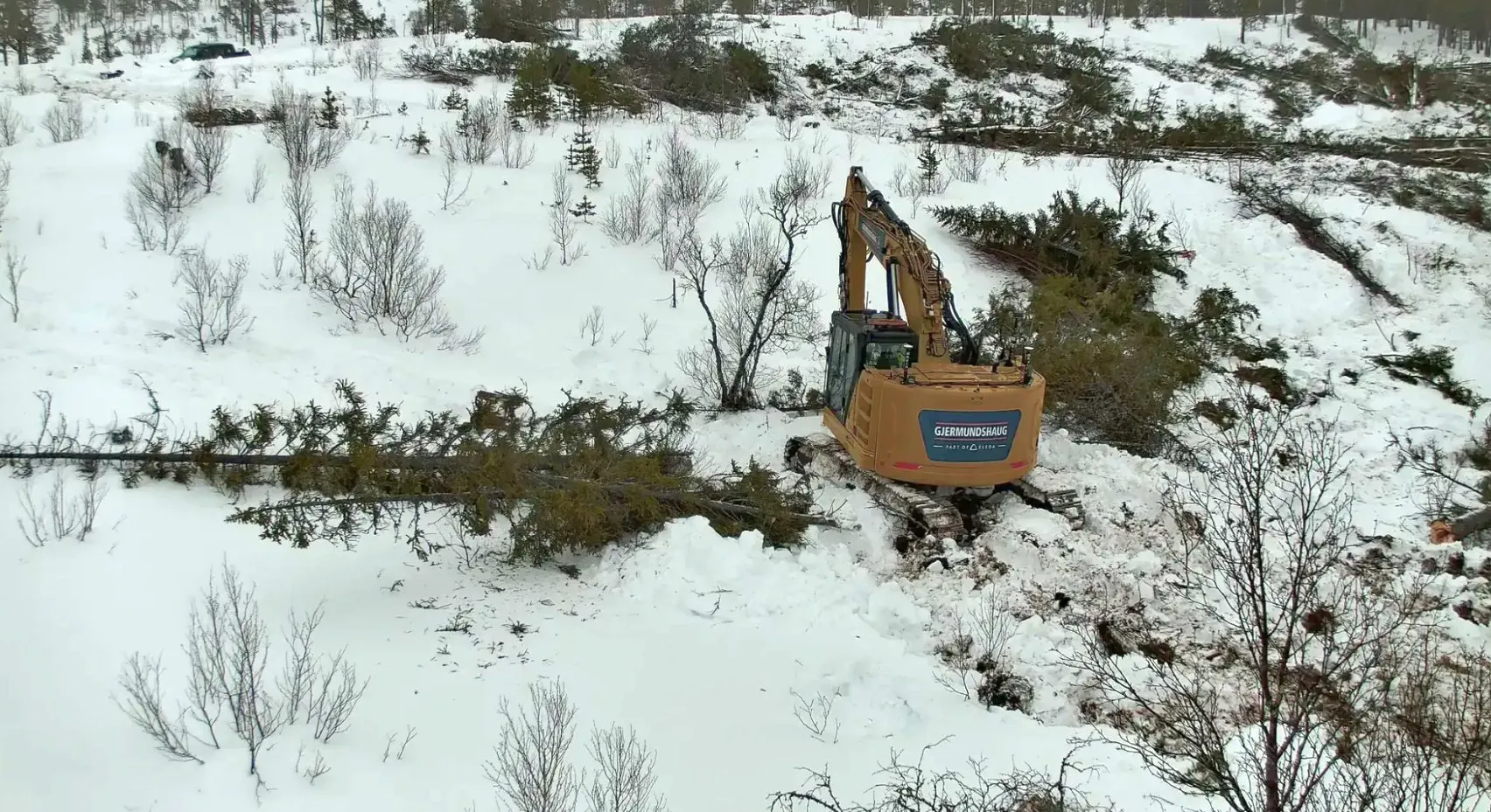 Excavator clearing trees and ground in snowy terrain during the Haltdalen Shooting Range project