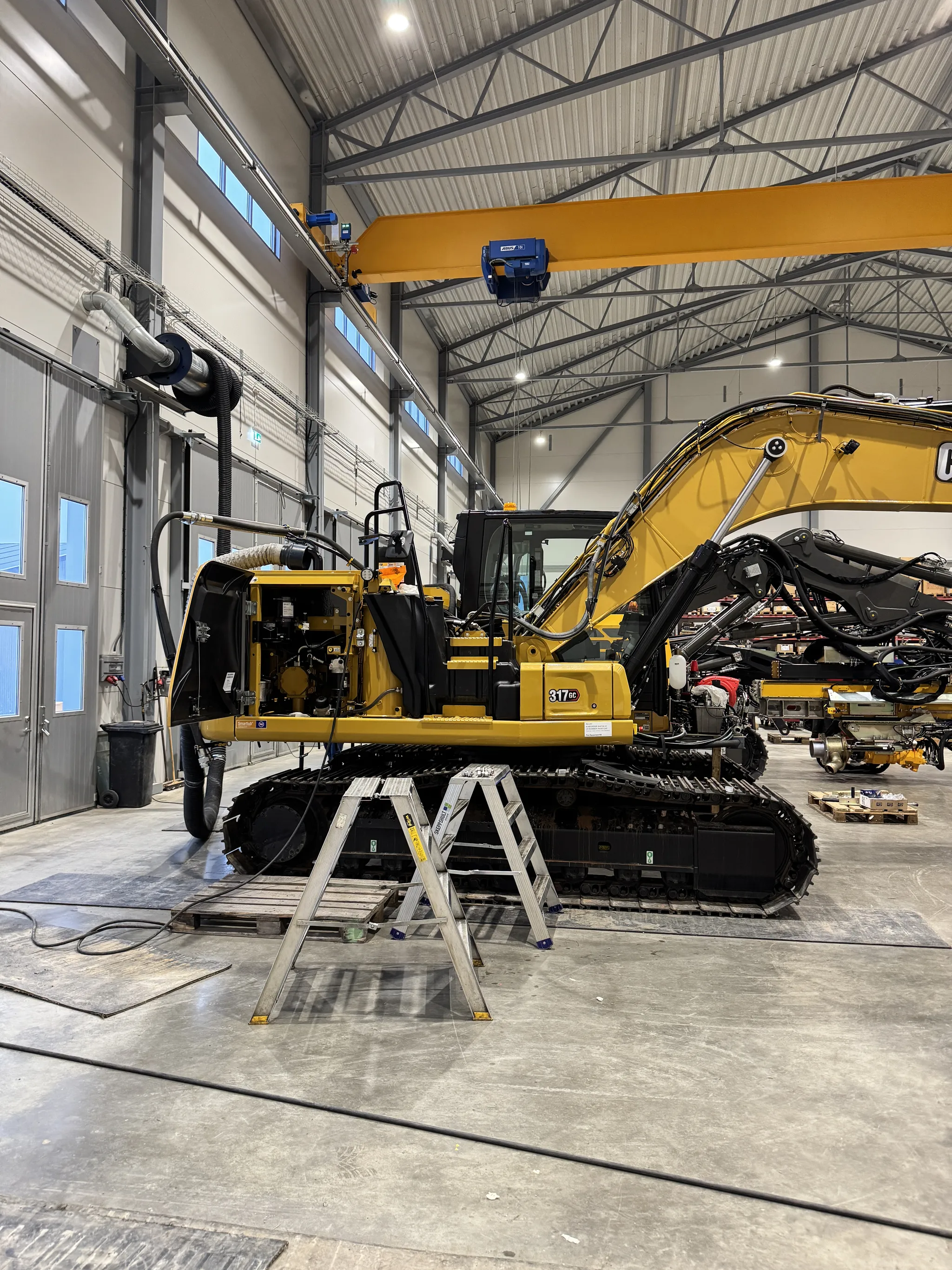 Remote-enabled CAT 317 excavator with advanced hydraulics undergoing setup in industrial workshop