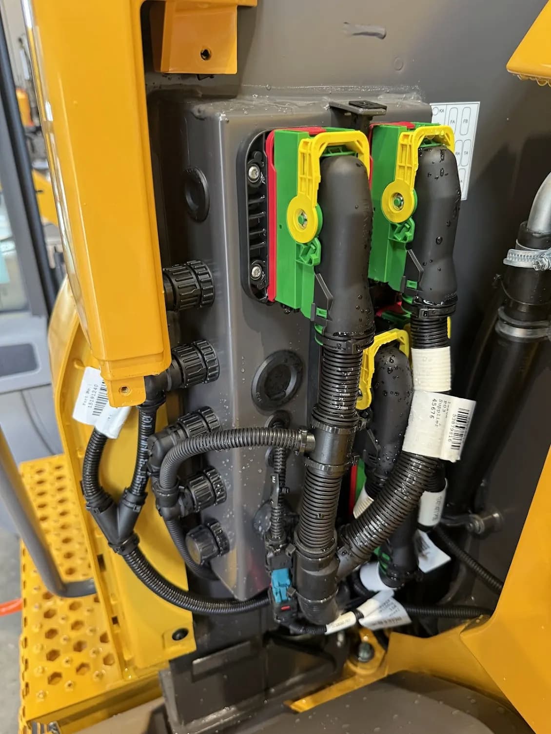 Close-up of the electrical control interface and connectors on a modified Volvo loader for teleoperated functions like lift, tilt, and throttle.
