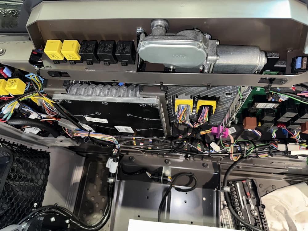 Close-up of the electrical control interface and connectors on a modified Volvo loader for teleoperated functions like lift, tilt, and throttle.