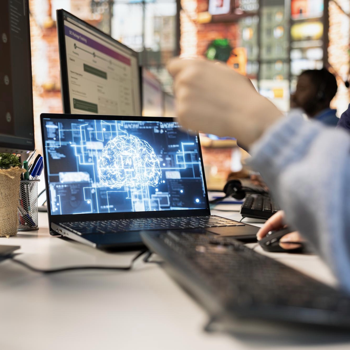 Person typing on a laptop displaying an AI network visualization