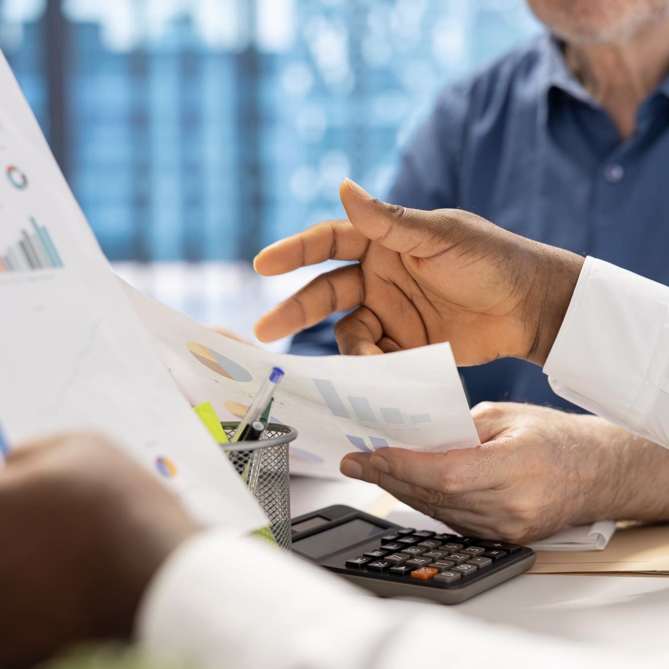 Close-up of hands reviewing printed charts and reports at a desk