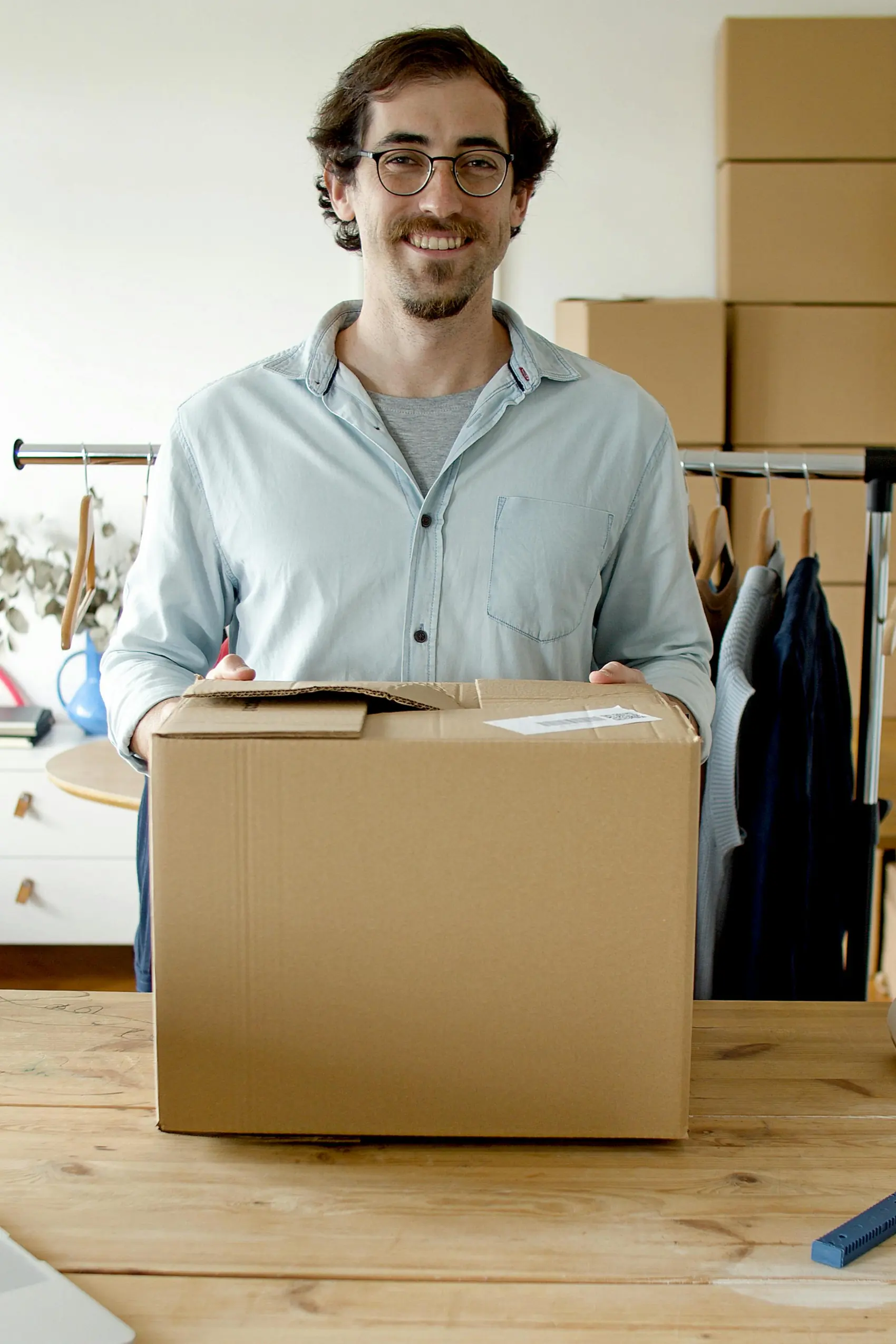 Hymyilevä tukkukaupan työntekijä pitelee pahvilaatikkoa valmiina toimitukseen.