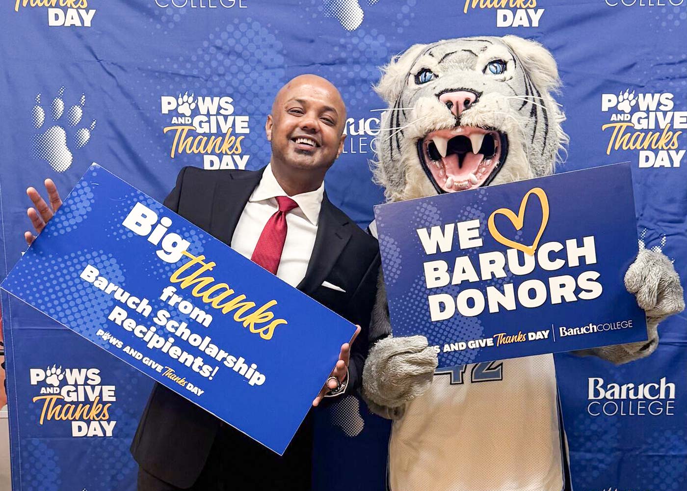 Baruch faculty member and mascot holding up a sign with a note of gratitude for Baruch donors