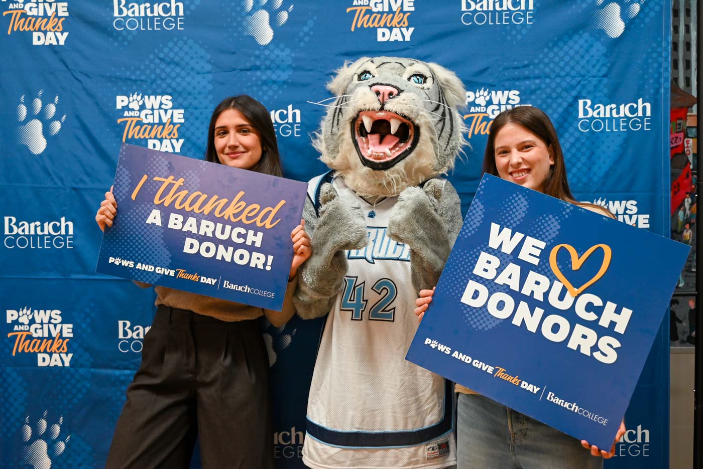 Baruch students and mascot holding up a sign with a note of gratitude for Baruch donors