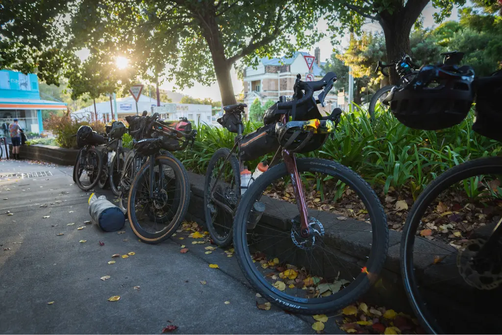 A row of gravel bikes parked next to each other on a sidewalk