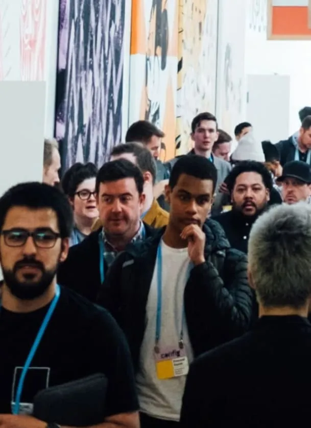 Groupe de personnes debout dans un couloir lors d'un événement ou d'une conférence, certaines portant des badges de participant.