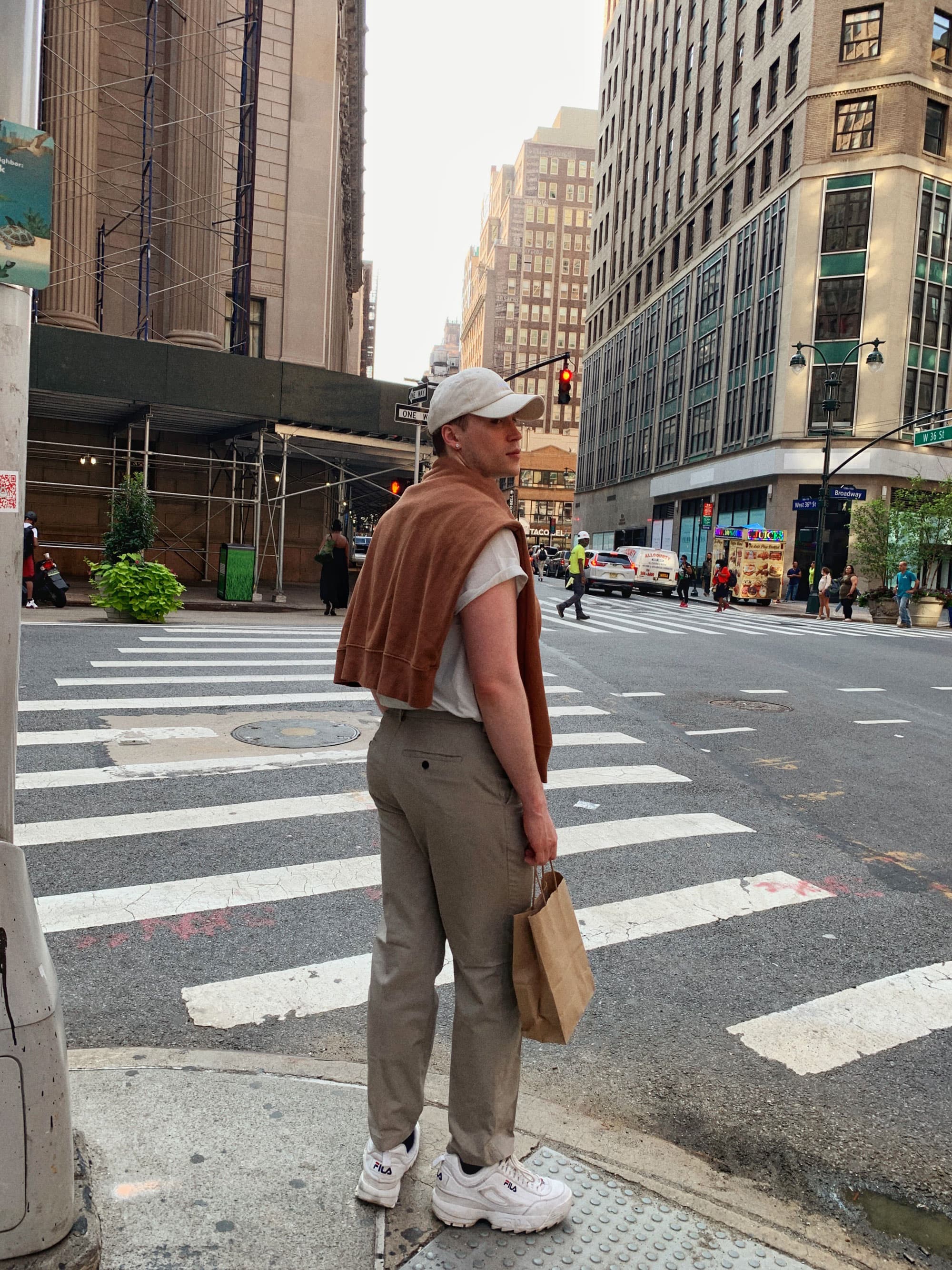 Liam standing on a city street corner in New York City, wearing a tan monochromatic outfit.