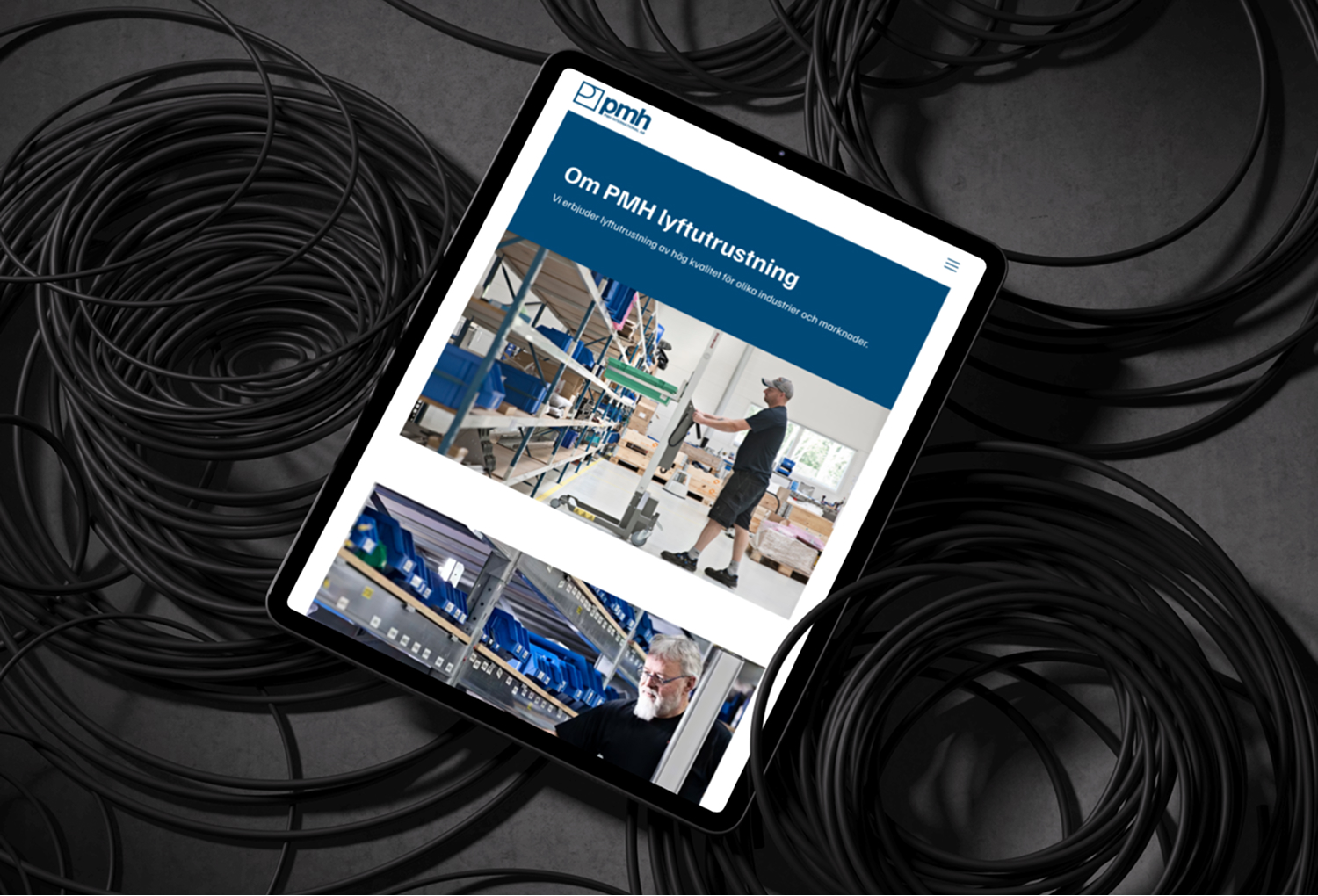 Surfplatta som visar PMH lyftutrustnings webbsida om industriell utrustning och kablar.