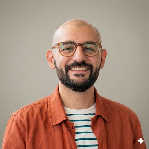 Hossein Lavi, Art Director at Atom Agency, smiling man with dark hair and beard wearing an orange jacket