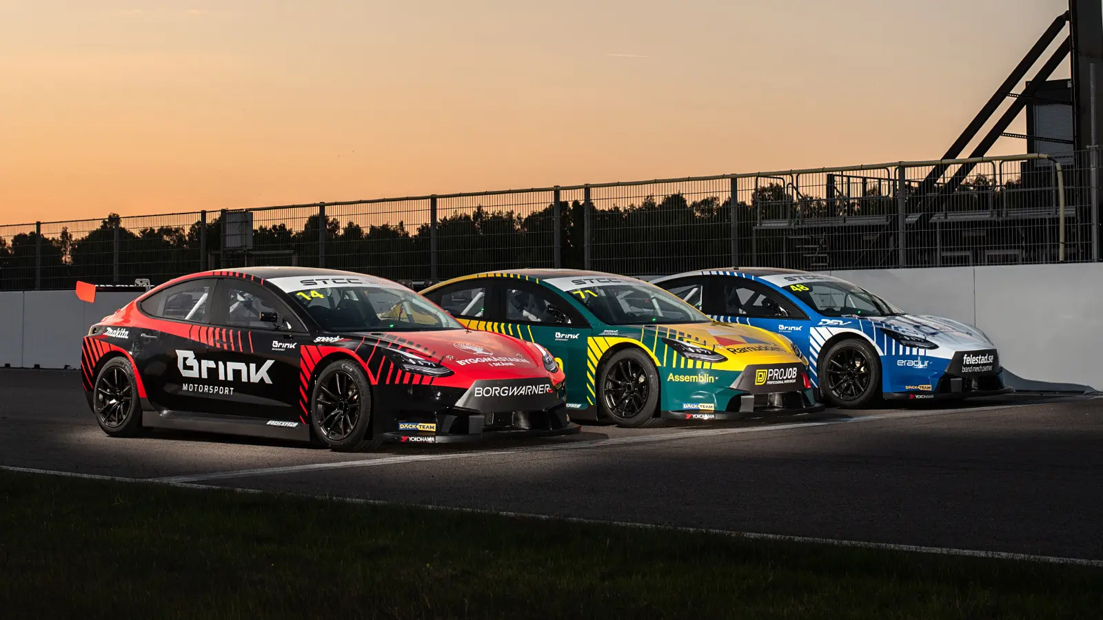 Racing cars on track at sunset, captured in motion during a professional motorsport event.