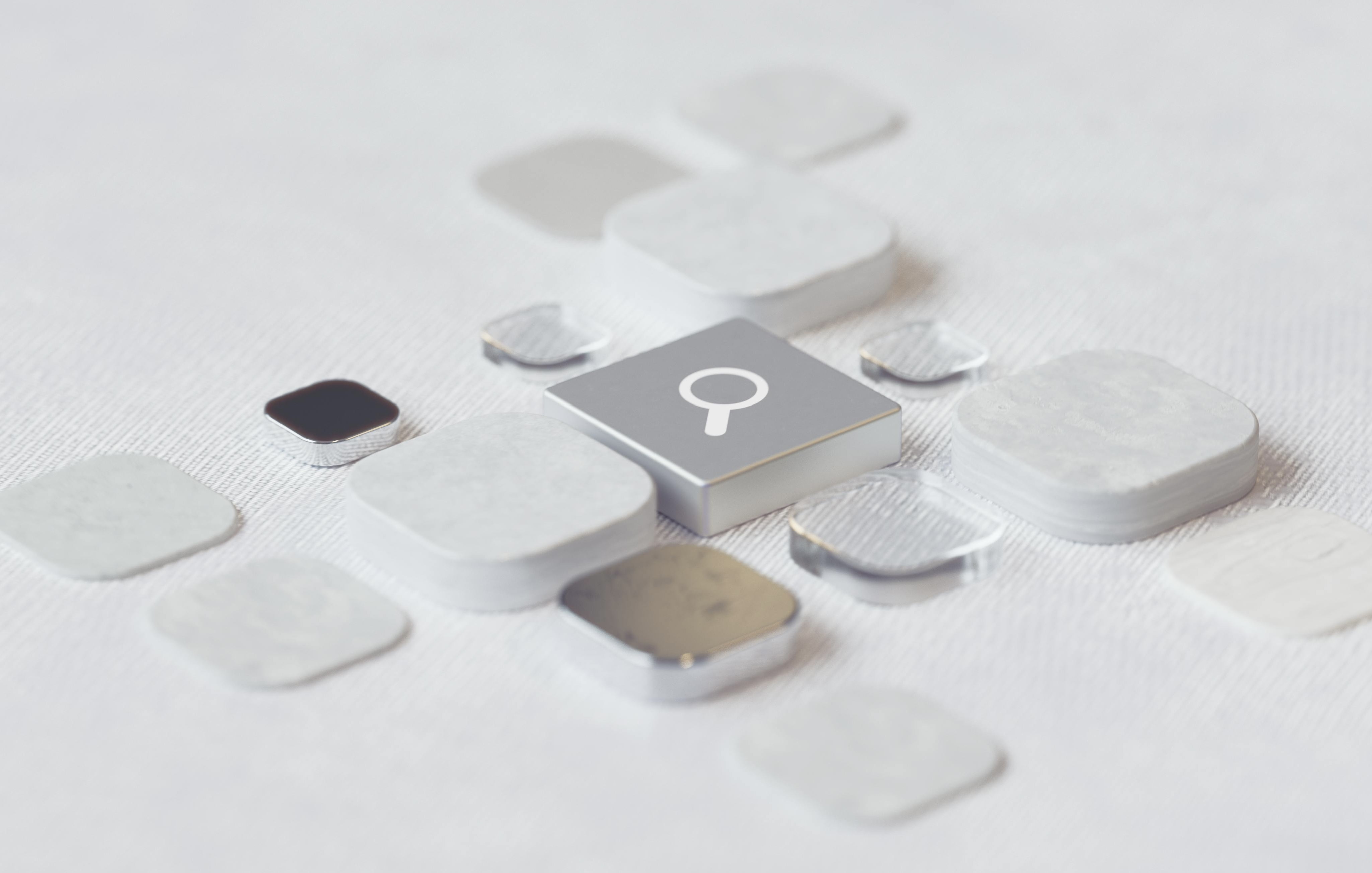 Grey and white Bluetooth trackers on a white background, small devices for locating items.