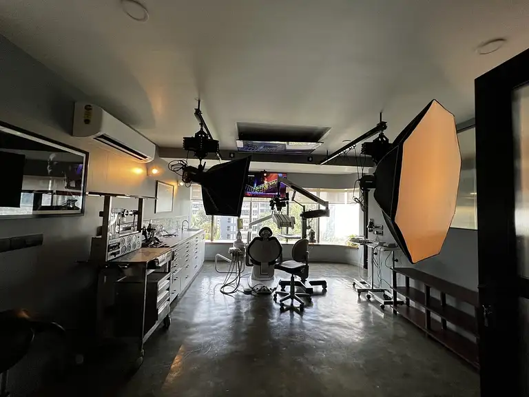Treatment room with a dental chair, overhead screens and a photography light
