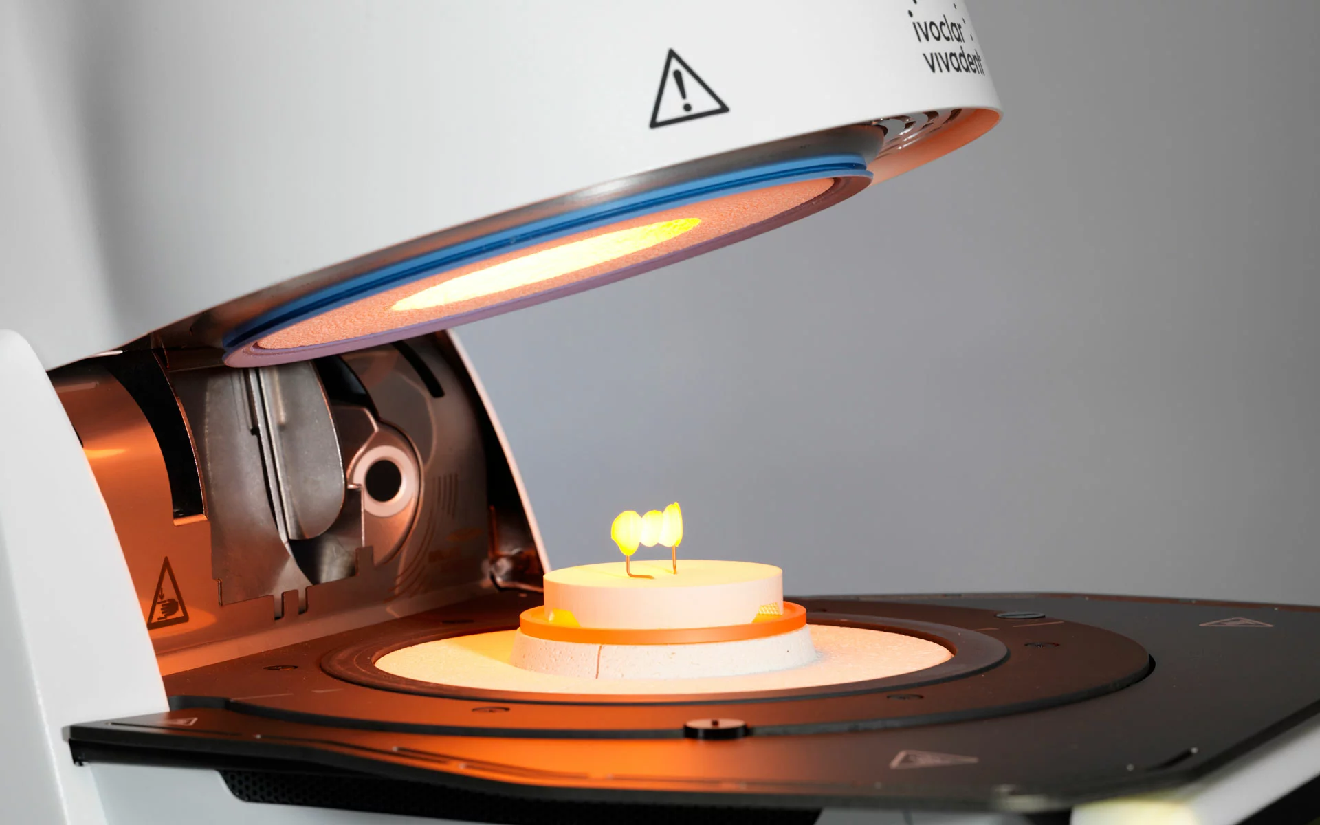 Ivoclar ceramic furnace, open, with a glowing crown on the firing tray