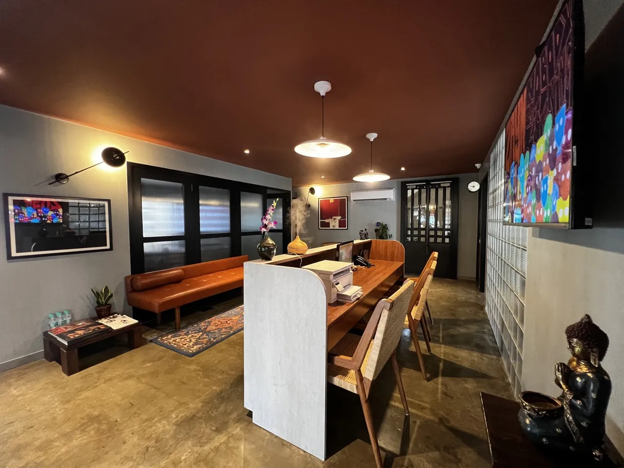 Bandra West reception with an orange sofa, a desk and wall art