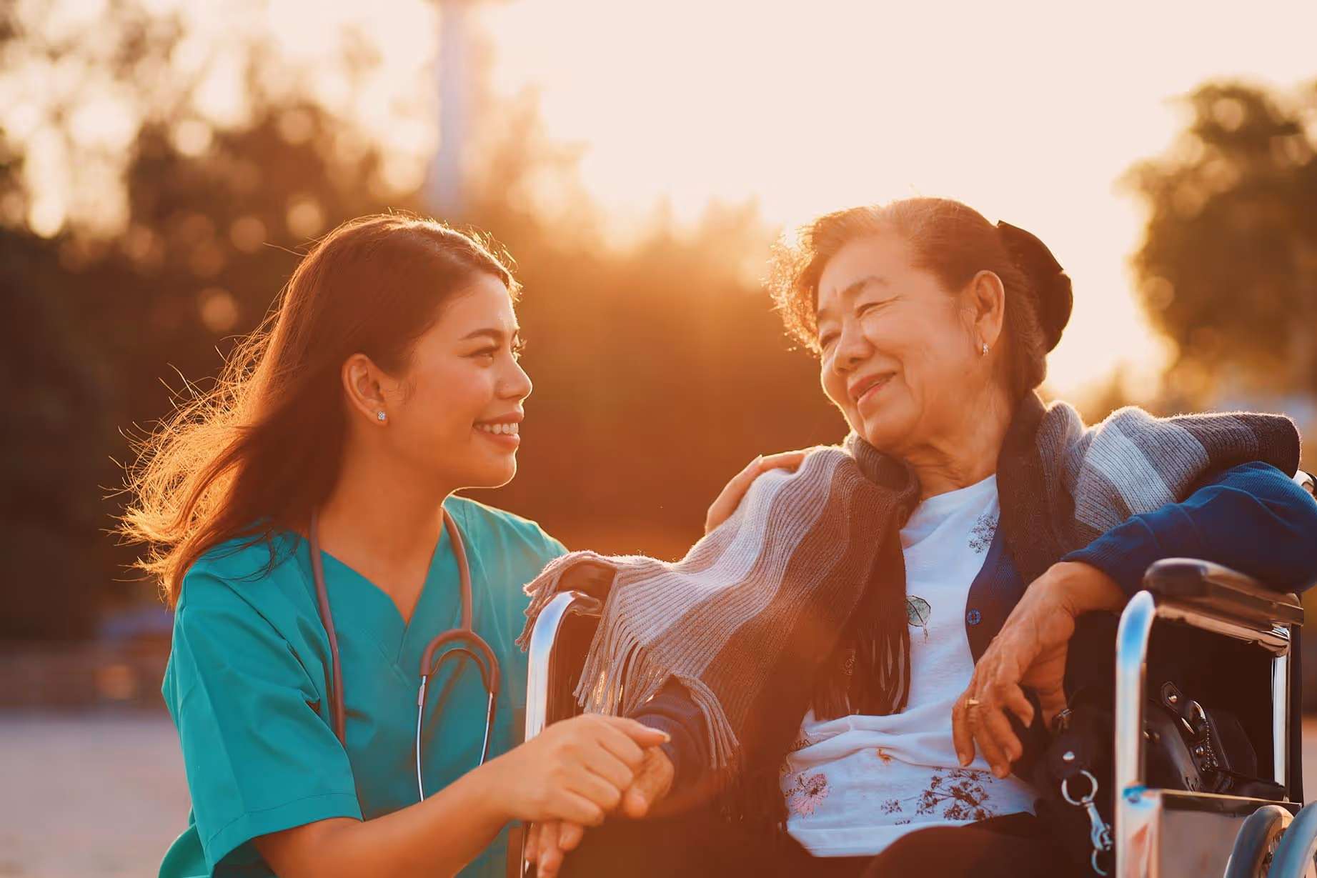 An Asian caregiver with her patient on a wheelchair.