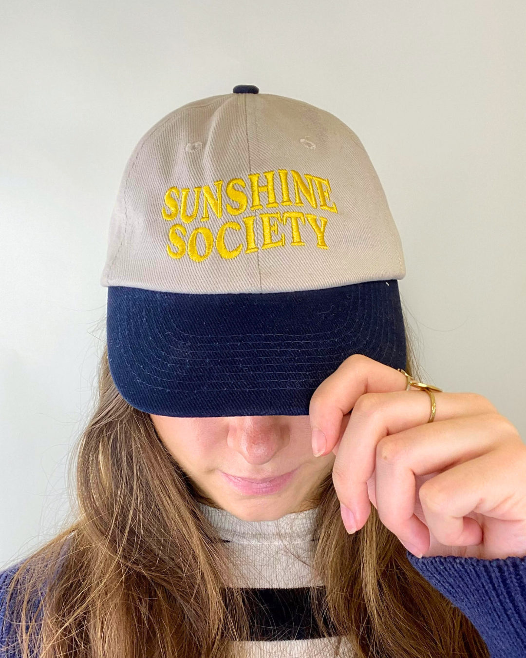 Femme qui porte une casquette Bleu et beige avec une broderie jaune dessus