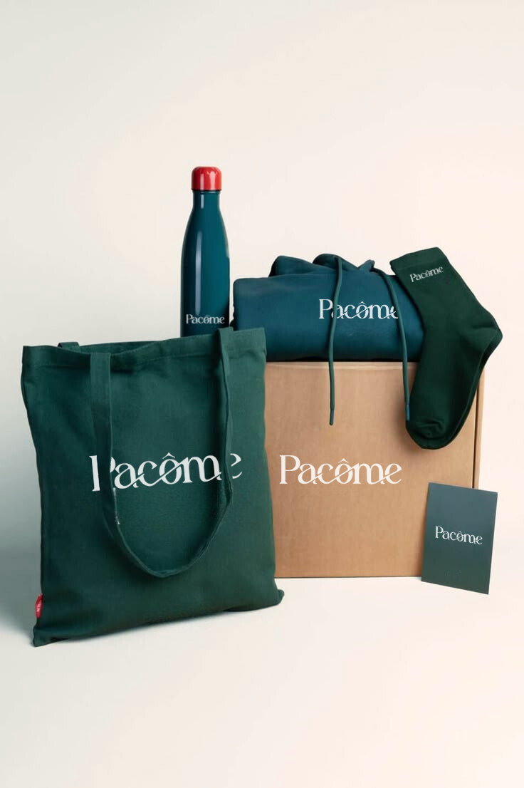 Un welcome pack avec : un tote bag, une gourde, un hoodie, une paire de chaussettes et un carnet vert foncé avec sur tous un marquage “Pacôme”, présentés autour d’un carton sur un fond uni beige.