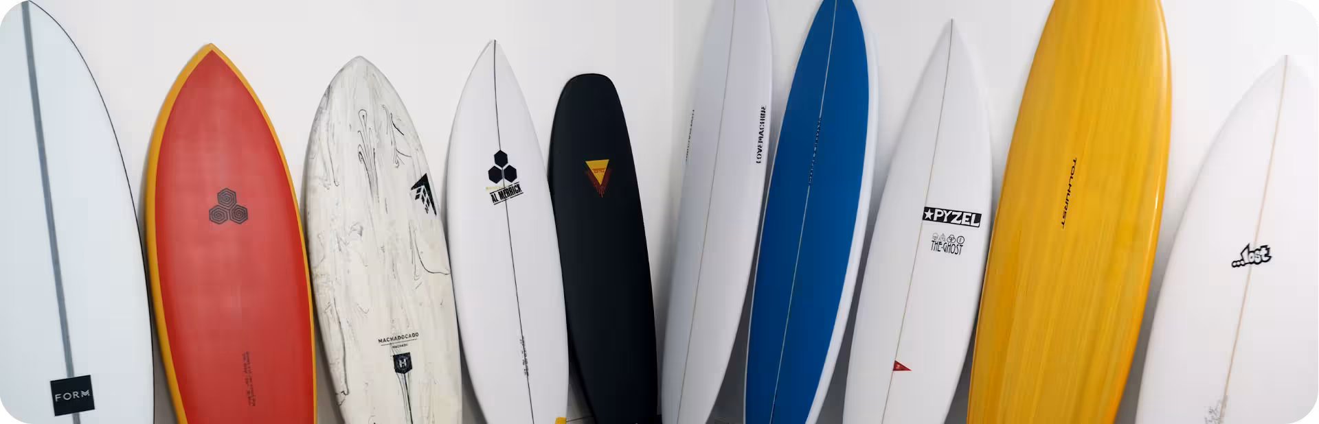 a variety of surfboards sitting against a wall