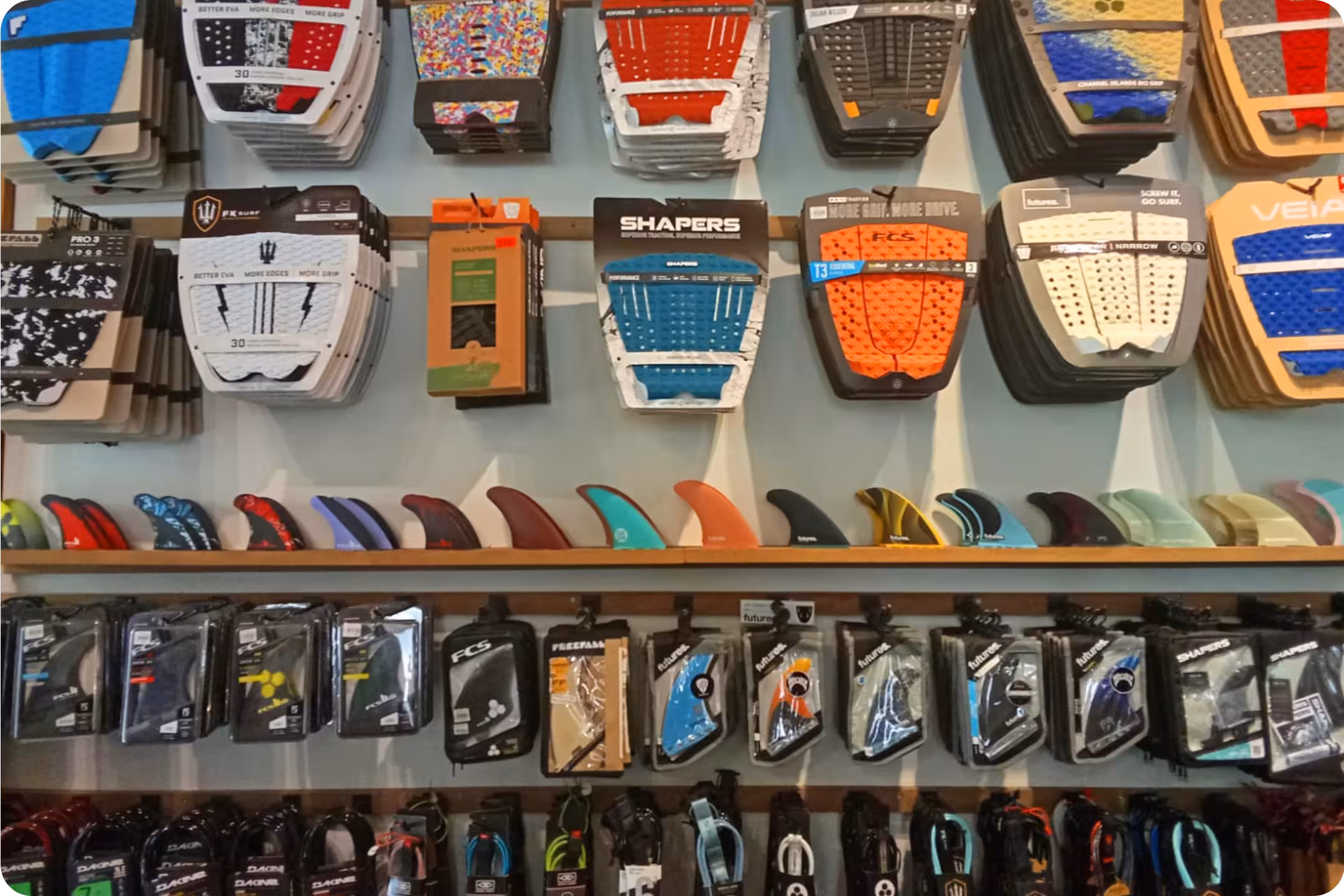 A surf supply rack with traction pads, fins and leashes