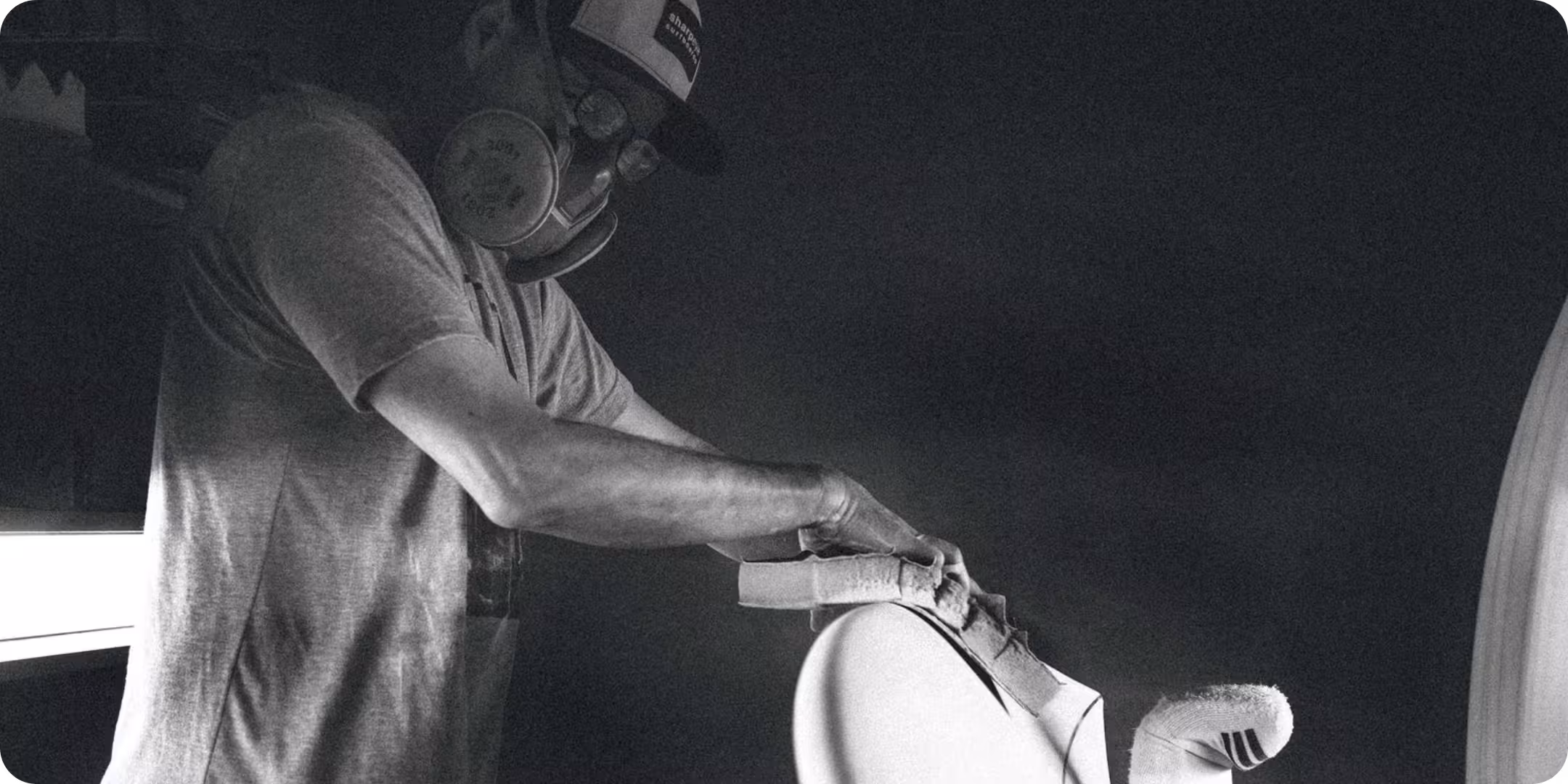 Marcio Zouvi shaping a surfboard in a black and white photo