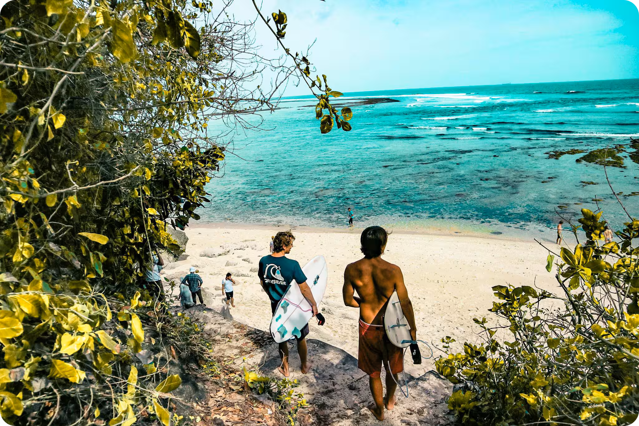 to men walking down a beach toward the reef with surf-able waves in the distance