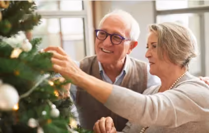 Old couple decorating a Christmas tree